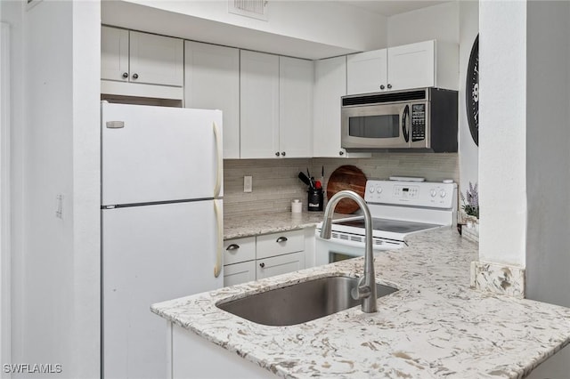 kitchen featuring sink, white cabinets, light stone counters, white appliances, and decorative backsplash