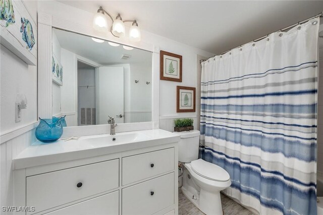 bathroom featuring curtained shower, toilet, and vanity