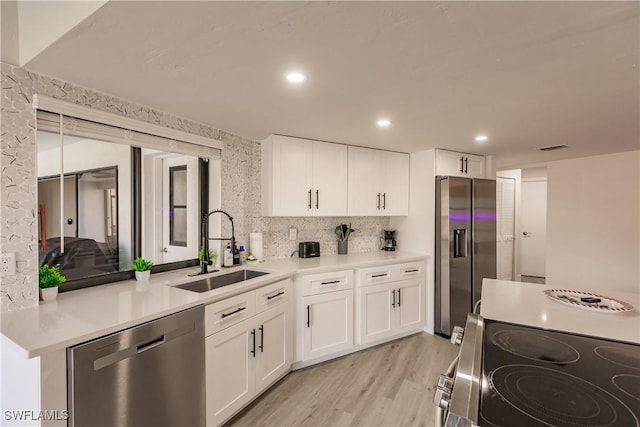 kitchen with sink, white cabinets, light hardwood / wood-style floors, and appliances with stainless steel finishes