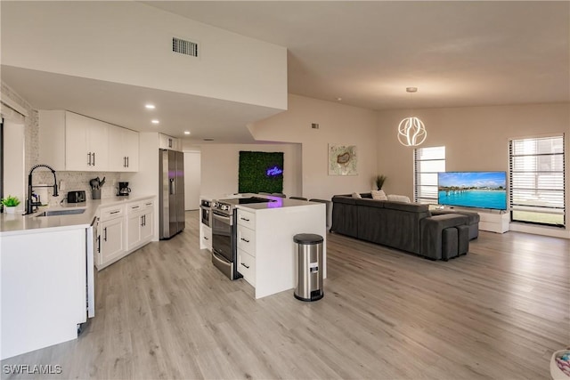 kitchen with stainless steel appliances, a sink, visible vents, open floor plan, and light wood finished floors