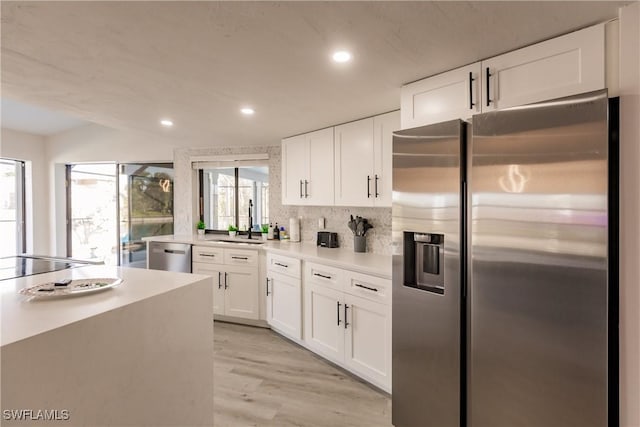 kitchen featuring light wood-style flooring, a sink, white cabinetry, light countertops, and appliances with stainless steel finishes