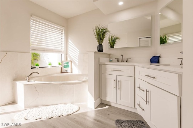 full bathroom with wood finished floors, vanity, and a bath