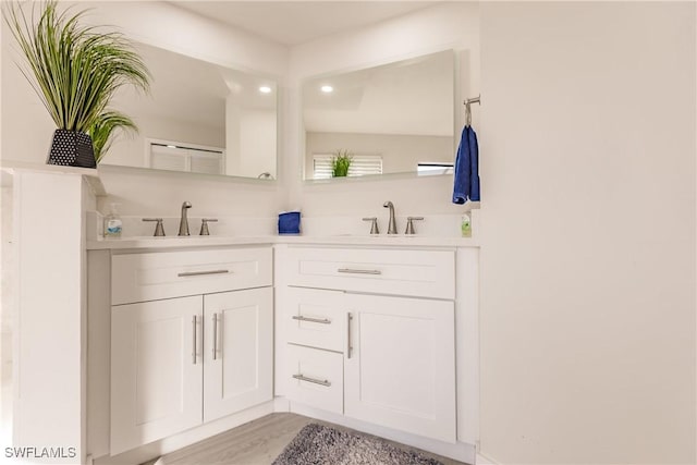 bathroom with double vanity, a sink, and wood finished floors