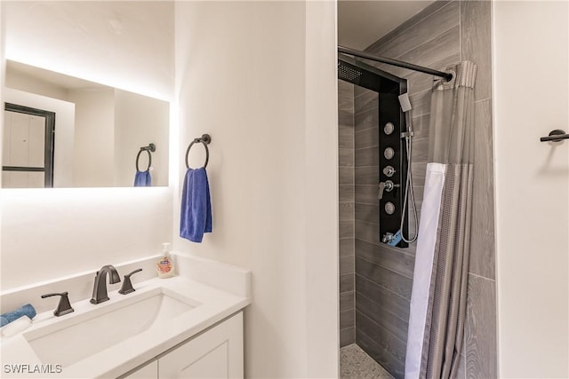 bathroom with a tile shower and vanity