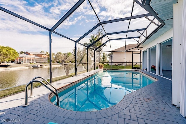 outdoor pool with glass enclosure, a patio area, and a water view