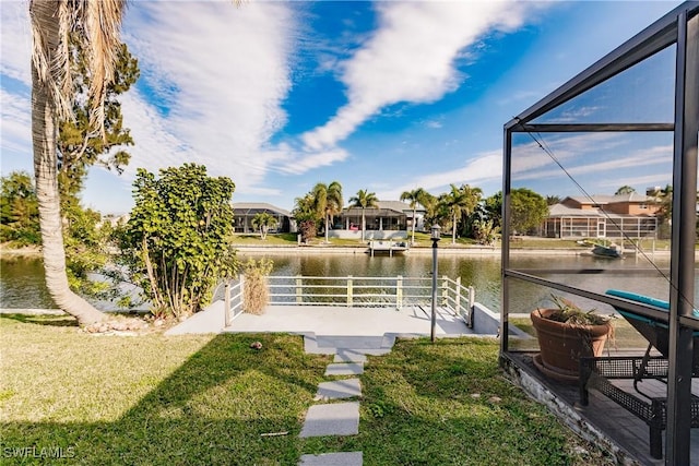 dock area featuring a lanai, a water view, and a yard