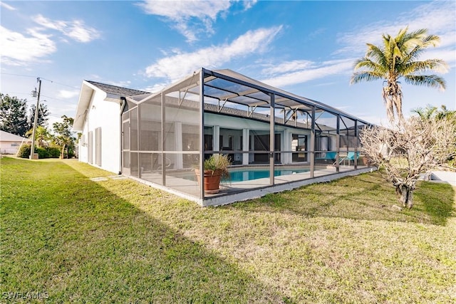 back of property featuring a lanai, an outdoor pool, a yard, stucco siding, and a patio area