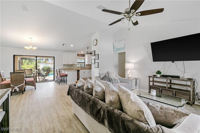 living room featuring ceiling fan with notable chandelier, light hardwood / wood-style floors, and lofted ceiling