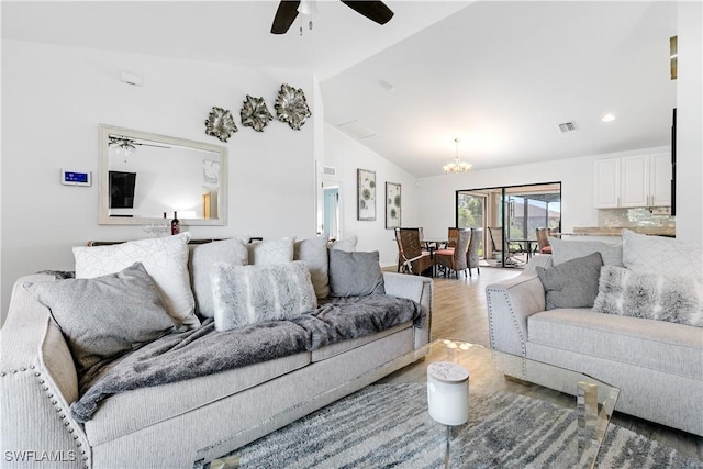 living room featuring ceiling fan with notable chandelier, wood-type flooring, and vaulted ceiling