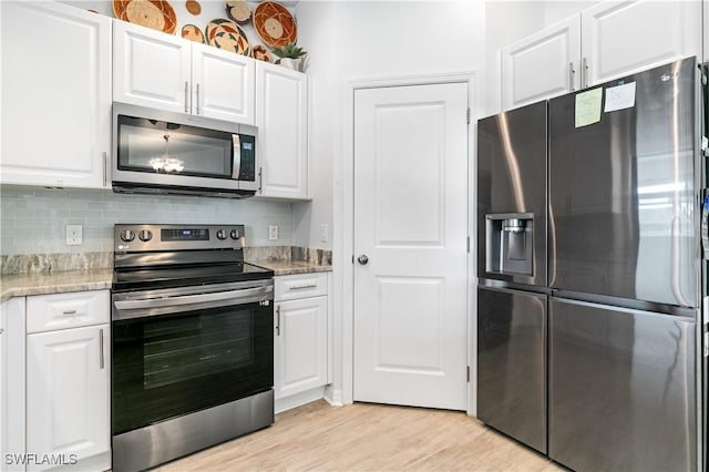 kitchen featuring light hardwood / wood-style flooring, decorative backsplash, light stone countertops, appliances with stainless steel finishes, and white cabinetry