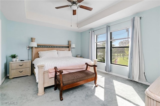 bedroom featuring light colored carpet, a raised ceiling, and ceiling fan