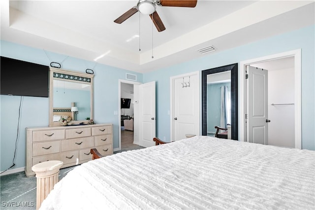 carpeted bedroom with ceiling fan and a tray ceiling