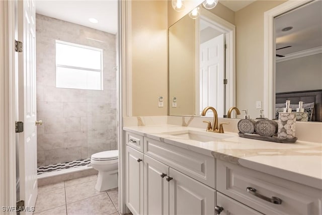 bathroom featuring ceiling fan, tile patterned floors, tiled shower, toilet, and vanity