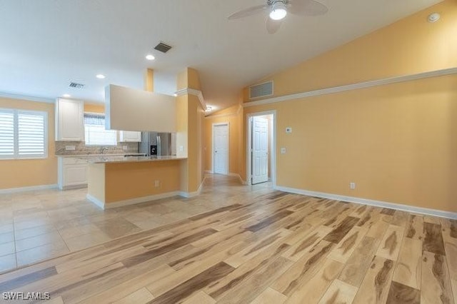 kitchen featuring lofted ceiling, backsplash, white cabinets, ceiling fan, and kitchen peninsula