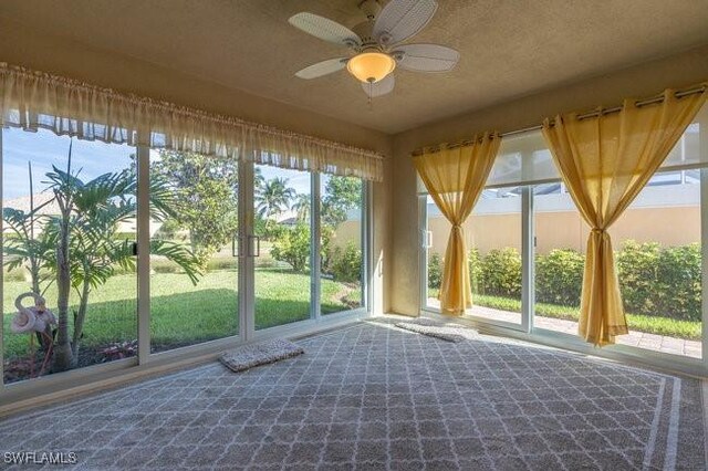 unfurnished sunroom with ceiling fan