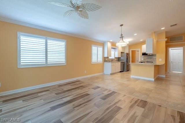 kitchen with white cabinets, ceiling fan, stainless steel fridge, decorative light fixtures, and light hardwood / wood-style floors