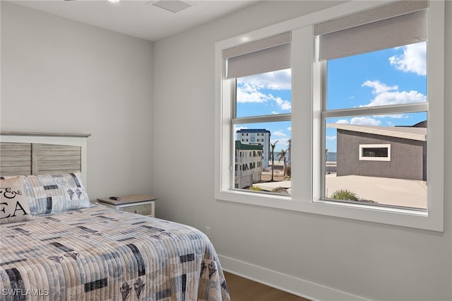 bedroom with wood finished floors, visible vents, and baseboards