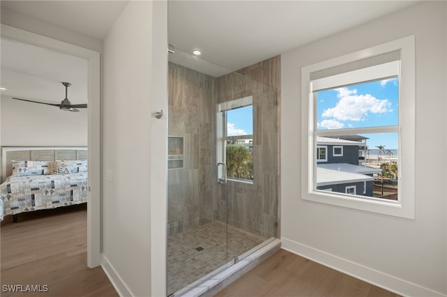 ensuite bathroom with recessed lighting, wood finished floors, a ceiling fan, baseboards, and a stall shower