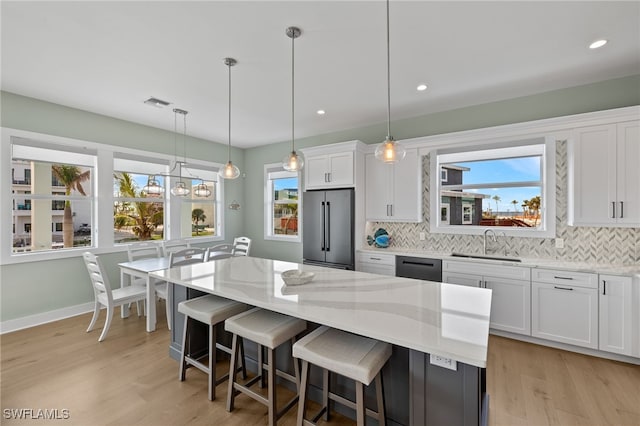 730 Matanzas Ct, Fort Myers Beach, FL 33931 - kitchen with white cabinets, a sink, appliances with stainless steel finishes, a kitchen bar, and decorative backsplash