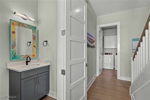 bathroom featuring independent washer and dryer, vanity, baseboards, and wood finished floors