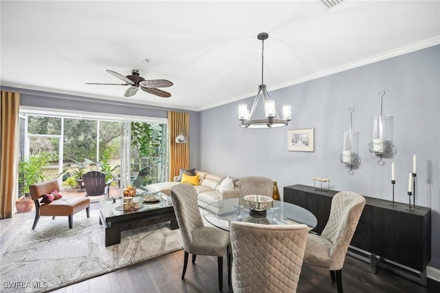 dining space with ornamental molding, ceiling fan with notable chandelier, and dark hardwood / wood-style flooring