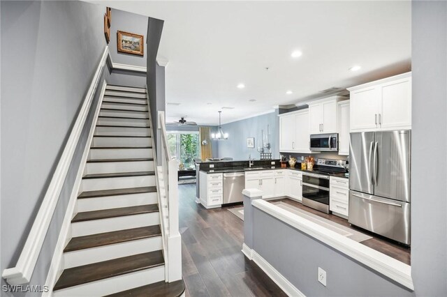 kitchen with appliances with stainless steel finishes, sink, white cabinets, and decorative light fixtures