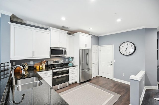 kitchen featuring appliances with stainless steel finishes, dark wood-type flooring, white cabinetry, dark stone countertops, and sink