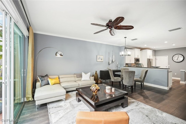 living room with ceiling fan with notable chandelier, dark wood-type flooring, and ornamental molding