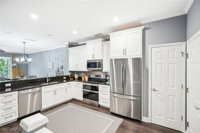 kitchen featuring stainless steel appliances, pendant lighting, white cabinets, and sink