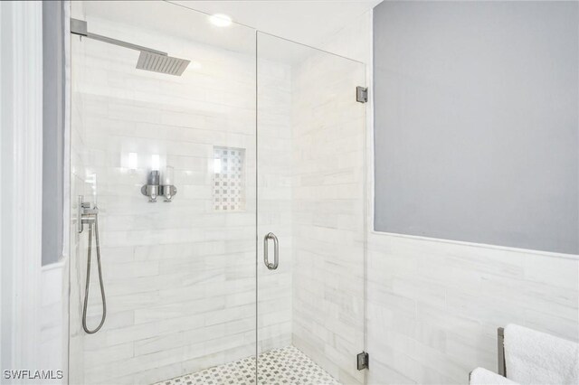 bathroom with a shower with shower door and tile walls