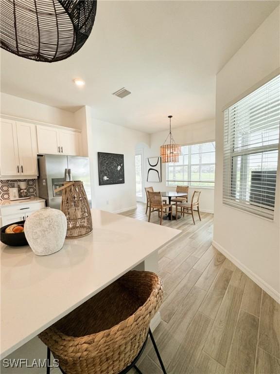 kitchen featuring white cabinets, backsplash, an inviting chandelier, and hanging light fixtures