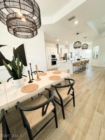 dining room with light hardwood / wood-style flooring and an inviting chandelier