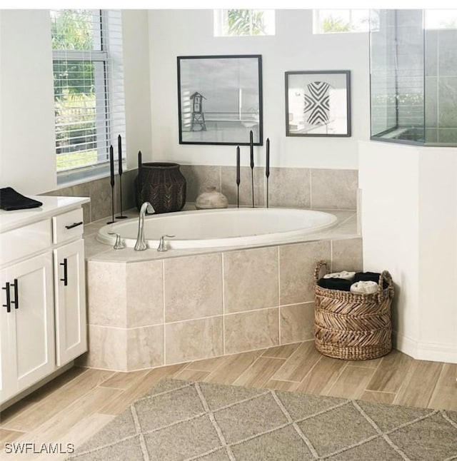 bathroom with vanity, tiled bath, and plenty of natural light