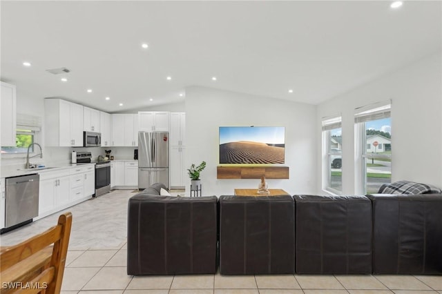 living room with sink, light tile patterned floors, and lofted ceiling