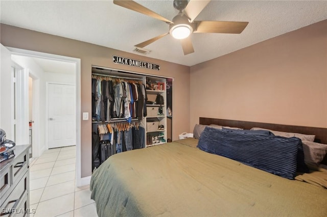 bedroom with light tile patterned floors, a textured ceiling, a closet, and ceiling fan