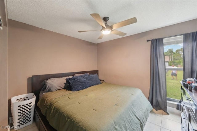 bedroom with ceiling fan, light tile patterned floors, and a textured ceiling