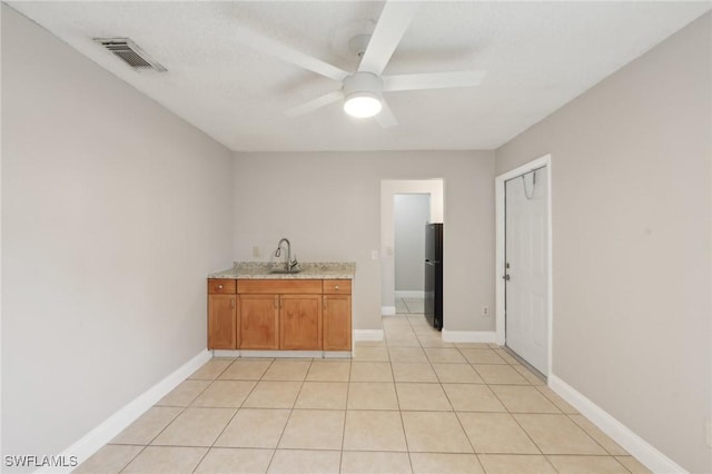 interior space with ceiling fan, black fridge, light tile patterned floors, and sink