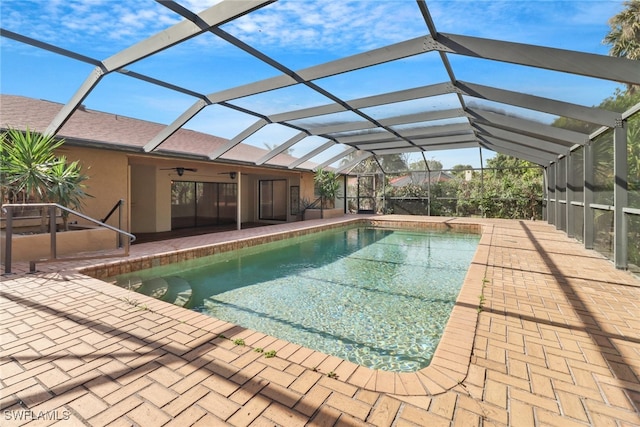 view of swimming pool featuring glass enclosure, ceiling fan, and a patio