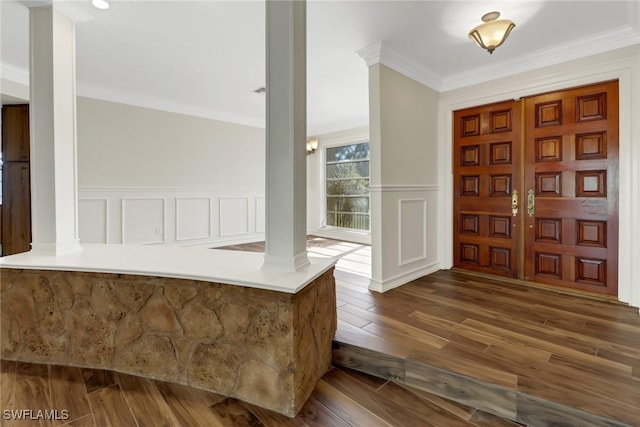 foyer entrance with dark hardwood / wood-style floors, ornamental molding, and ornate columns