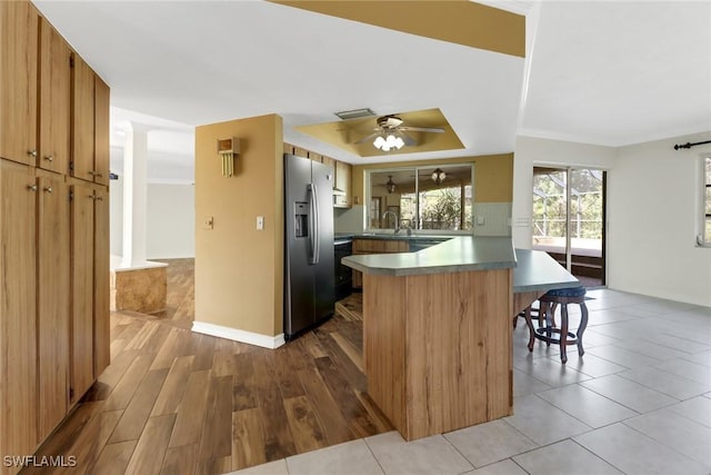 kitchen with a breakfast bar, sink, ceiling fan, stainless steel fridge, and kitchen peninsula