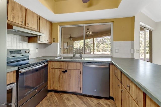 kitchen with appliances with stainless steel finishes, backsplash, ceiling fan, sink, and light hardwood / wood-style flooring