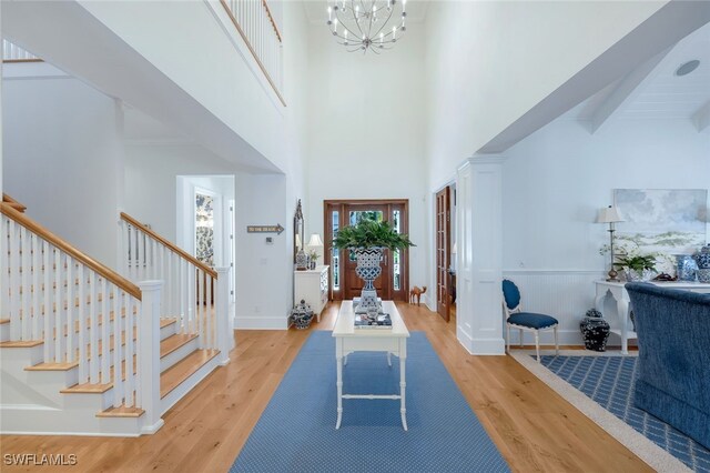 entrance foyer with light hardwood / wood-style floors, a high ceiling, beamed ceiling, and a chandelier