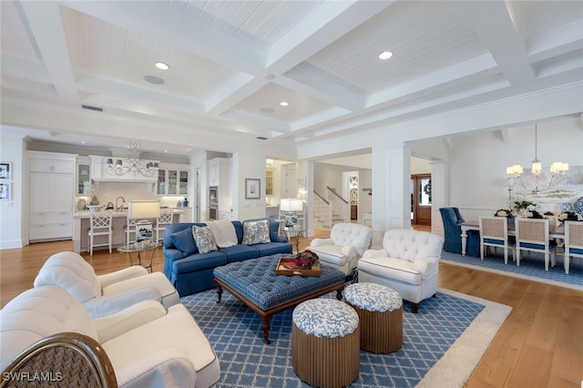 living room with an inviting chandelier, coffered ceiling, hardwood / wood-style floors, ornamental molding, and beamed ceiling