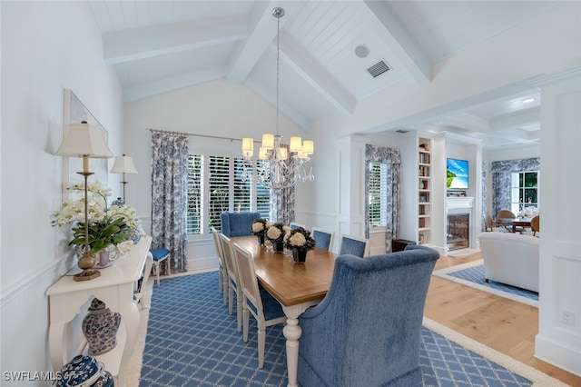 dining space with hardwood / wood-style floors, a wealth of natural light, and an inviting chandelier