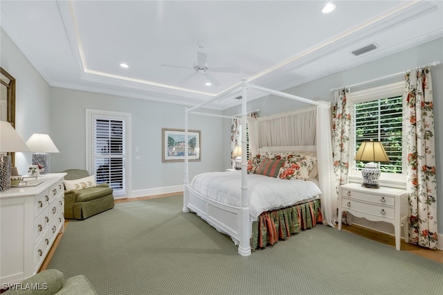 carpeted bedroom with ceiling fan and a raised ceiling