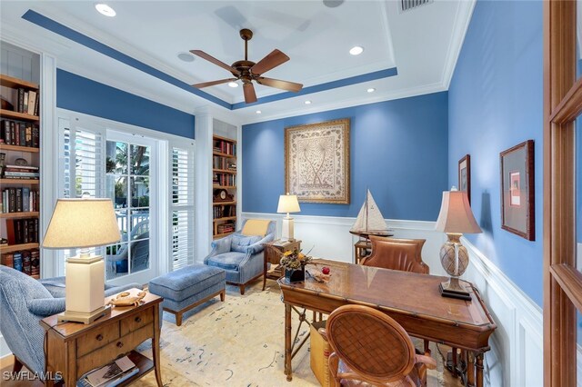 office space featuring crown molding, built in shelves, ceiling fan, and a tray ceiling