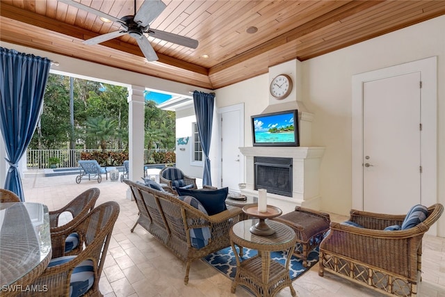 living room with ceiling fan, an outdoor fireplace, and wood ceiling