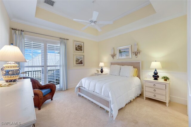 carpeted bedroom with ceiling fan, crown molding, and a tray ceiling