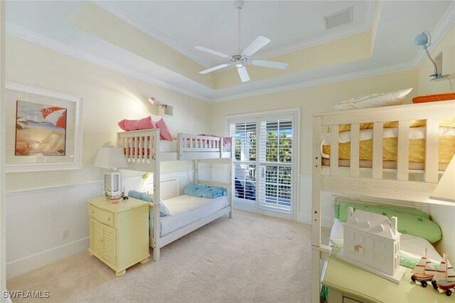 carpeted bedroom featuring ceiling fan, access to outside, crown molding, and a tray ceiling