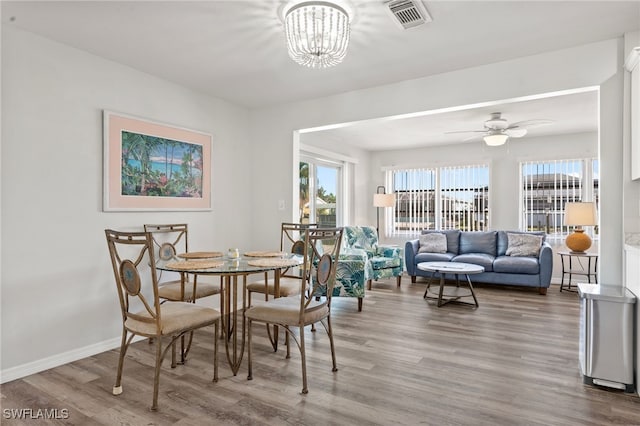 dining space with hardwood / wood-style floors and ceiling fan with notable chandelier